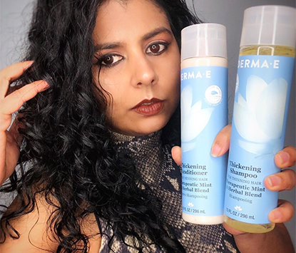 woman with 2c hair holding derma e's shampoo and conditioner