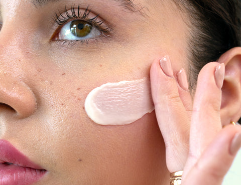 close-up of woman spreading retinol cream on her cheek
