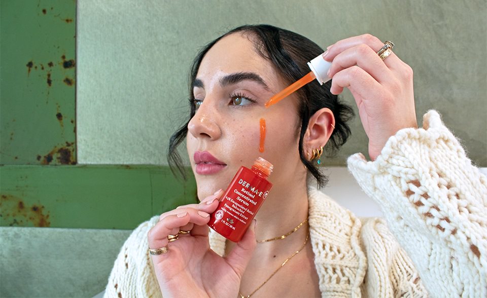 Girl holding up a bottle of DERMA E's retinol serum for anti-aging